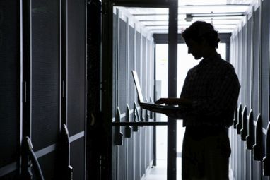 Un ingénieur dans l'ombre opérant dans un data center sécurisé